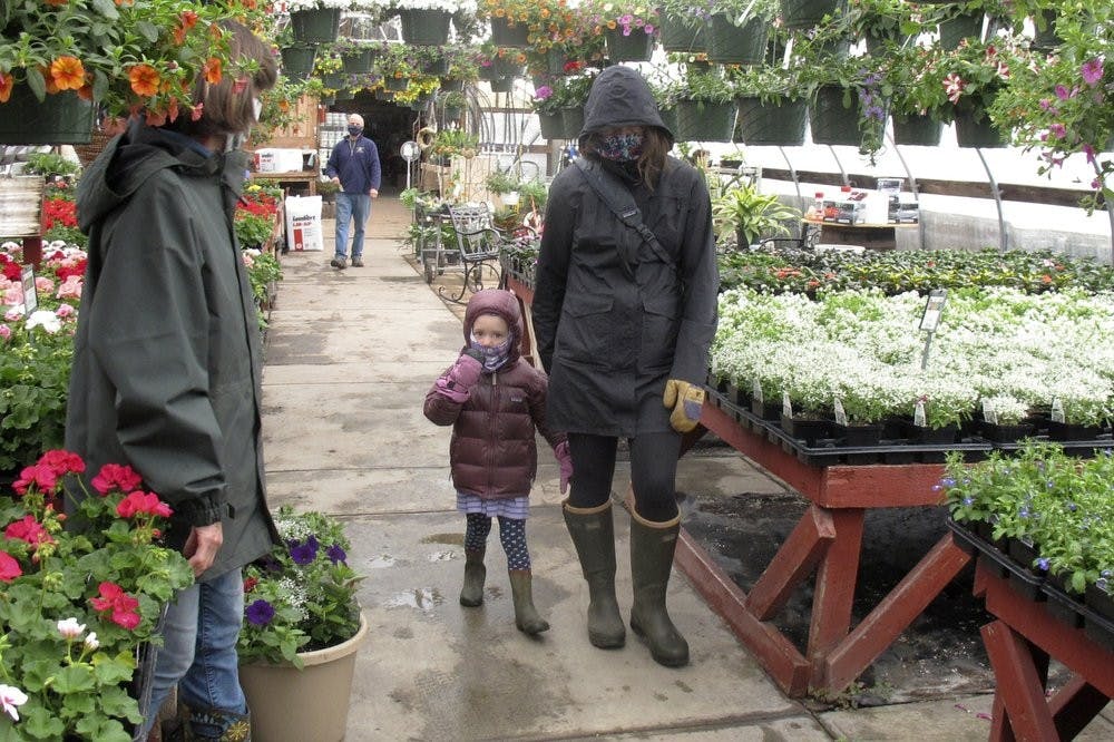 Kim and 4-year-old Marley Farwell, of Stowe, Vt., walk through the greenhouse at Evergreen Gardens of Vermont April 27, 2020, in Waterbury Center, Vt. Monday was the the first day businesses such as greenhouses and garden centers could allow a small number of customers inside as part of Vermont's gradual coronavirus pandemic reopening plan. (AP Photo/Wilson Ring)