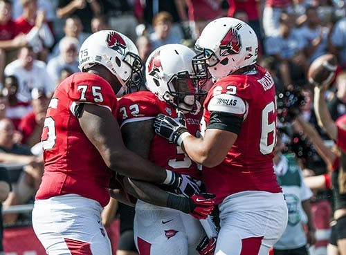 Matthew Page and Jacob Richard congratulate Jahwan Edwards after he completes a touchdown against Toledo on Sept. 28. DN PHOTO JONATHAN MIKSANEK