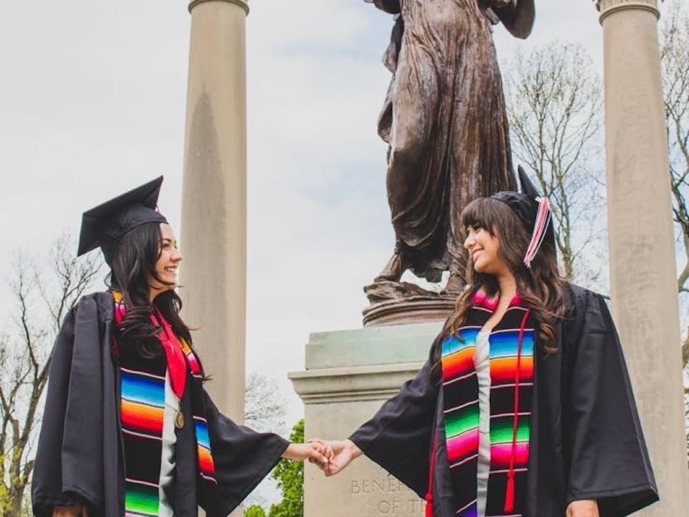 Spring 2022 Ball State University graduate Abril Castaneda and her friend pose with Beneficence on Ball State's campus in Muncie, Indiana. The women are dressed in their cap and gowns they will wear during the commencement ceremony May 7. 