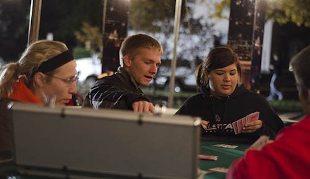 Luke Morrow, a sophomore business major and Brittany Overstreet, a photojournalism sophomore have small talk as they play a casual game of poker Monday night at the homecoming village. The homecoming village hosted multiple venues for students including a poker tournament tent, a rock wall and a zip line. DN FILE PHOTO COREY OHLENKAMP
