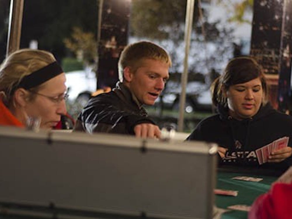 Luke Morrow, a sophomore business major and Brittany Overstreet, a photojournalism sophomore have small talk as they play a casual game of poker Monday night at the homecoming village. The homecoming village hosted multiple venues for students including a poker tournament tent, a rock wall and a zip line. DN FILE PHOTO COREY OHLENKAMP