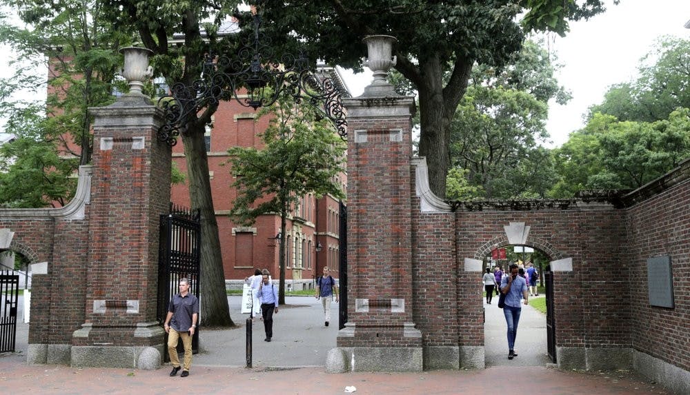Pedestrians walk through the gates of Harvard Yard at Harvard University Aug. 13, 2019, in Cambridge, Mass. Harvard and Massachusetts Institute of Technology filed a federal lawsuit July 8, 2020, challenging the decision to bar international students from staying in the U.S. if they take classes entirely online this fall. (AP Photo/Charles Krupa, File)