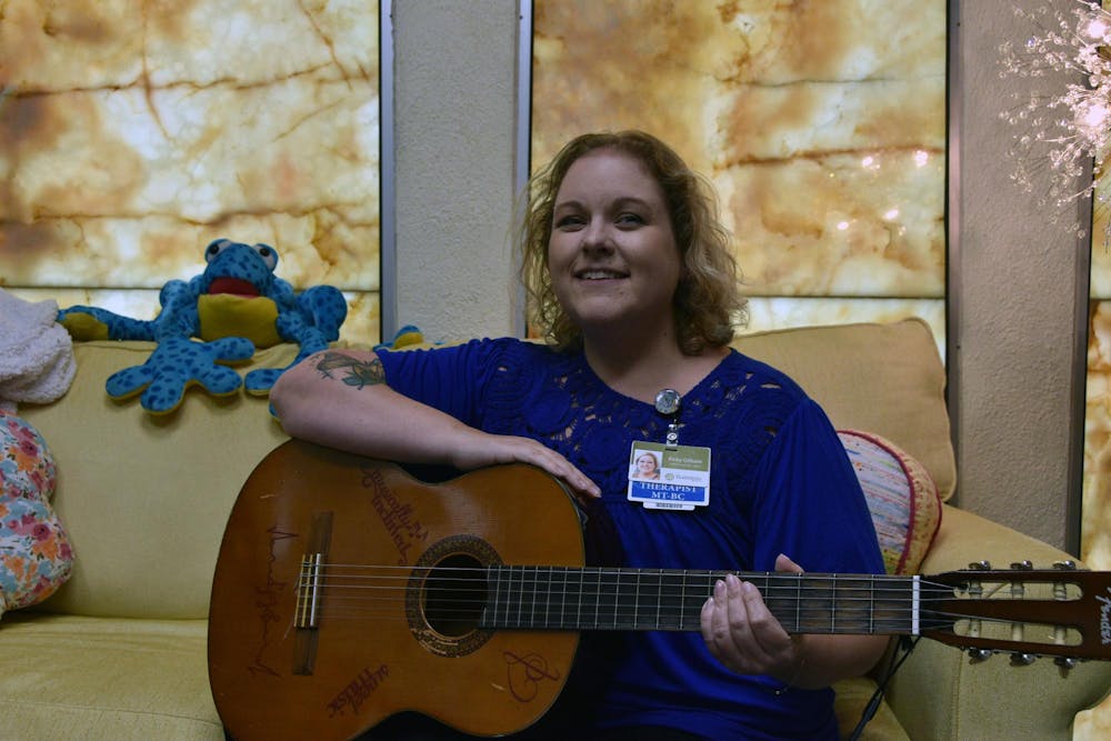 Kirby Gilliam holds her guitar on the couch in her office Aug. 15 at Plainsong Music Services. Gilliam says her music therapy patients each have a unique plan based on their goals. Ella Howell, DN