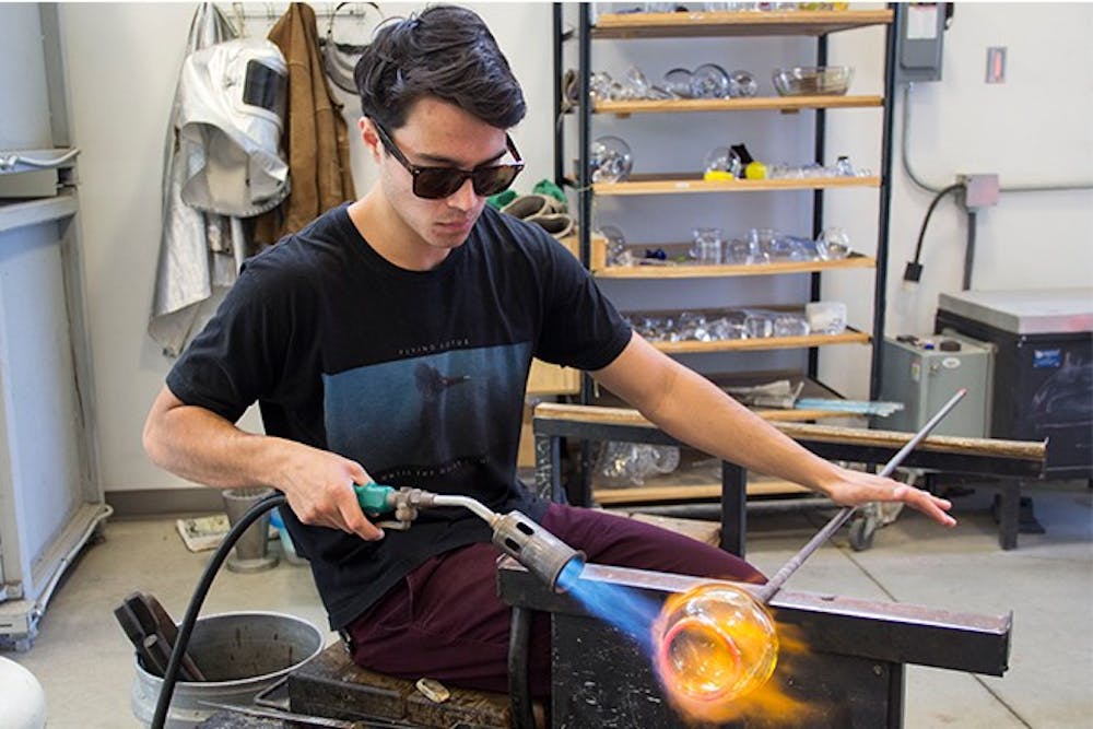 <p><em>Dils flame polishes his glass piece. Dils said he works in the studio for approximately 15 to 20 hours a week.</em></p>
