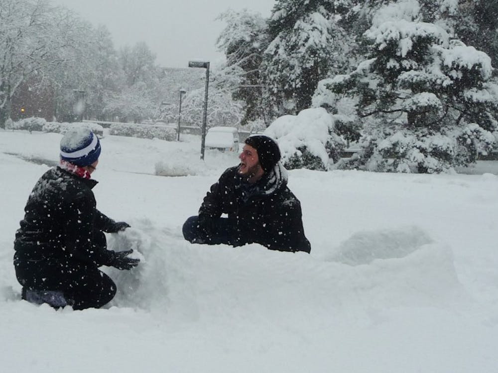 Gabe Weaver, a sophomore visual communications major and Katie Clark, a sophomore hospitality and food management major, crouch in the snow near Bracken Library. The two built the fort a few hours before the winter storm intensified. DN PHOTO SAM HOYT