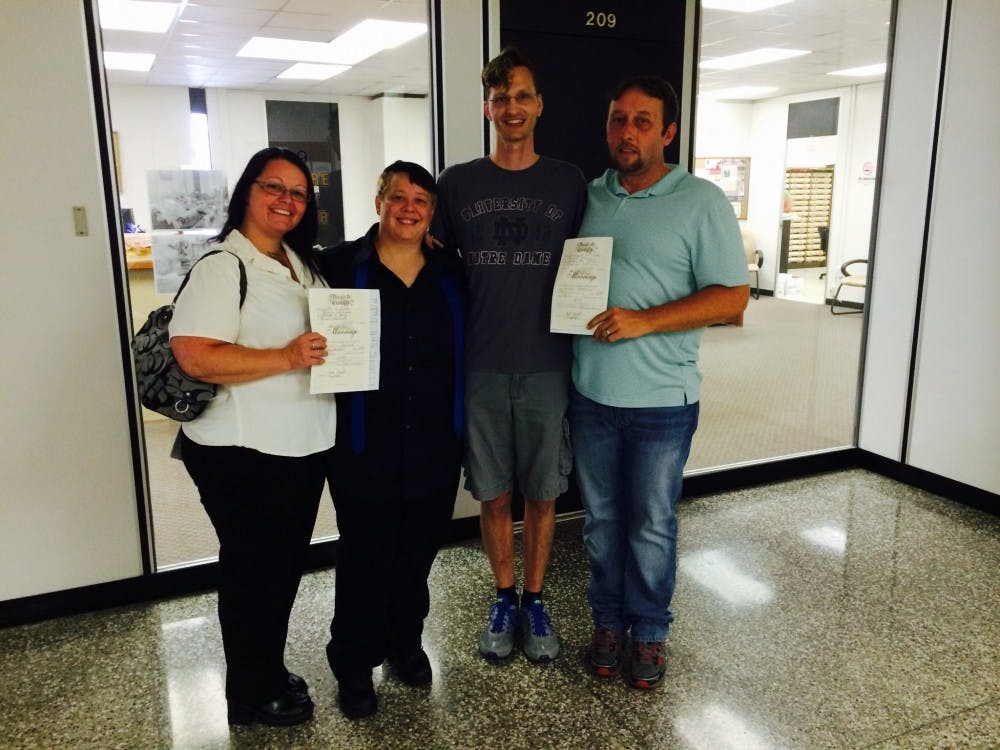 Natasha Martz, Heather Dobbs, Jathan Coker and Jeremy Phatterson hold up their marriage licenses after receiving them June 26 at the Delaware County Clerk