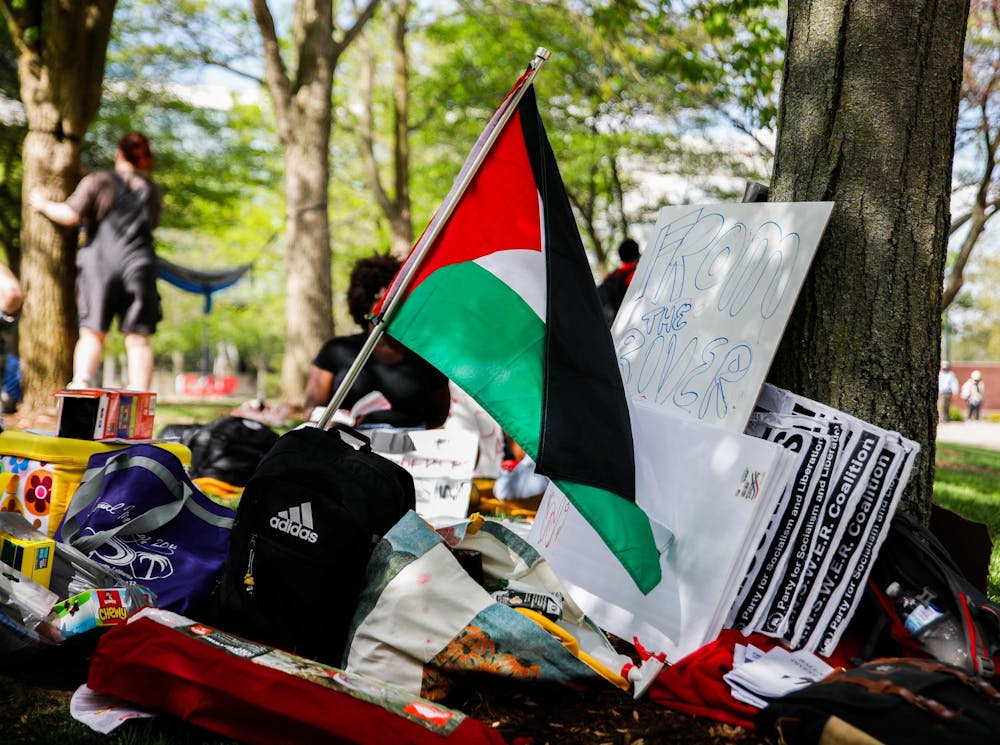 Food, tents and water sit next to the flag of Palestine during a student-led protest May 1st at Frog Baby Fountain. Students plan to be on the University Green for a couple of hours. Andrew Berger, DN 