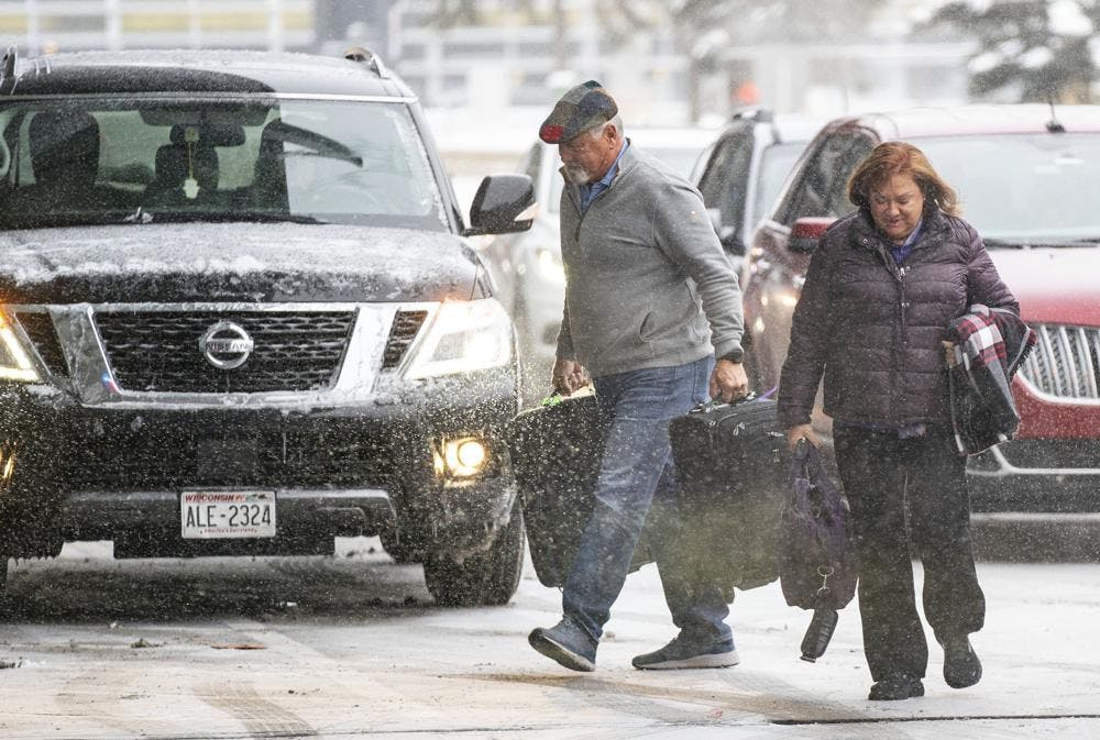 Travelers walk through the snow into Terminal 1 Wednesday, Dec. 21, 2022 at the Minneapolis-Saint Paul International Airport in Minneapolis. (Alex Kormann /Star Tribune via AP)