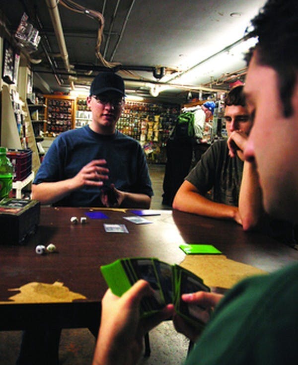 Freshman Peter Reilly and Junior Ryan McCorkle shuffle their cards while Sophomore Brian Cox watch the game's progress. The three friends frequent the Wizards Keep several times a week to play. DN PHOTO/Kyle Peters