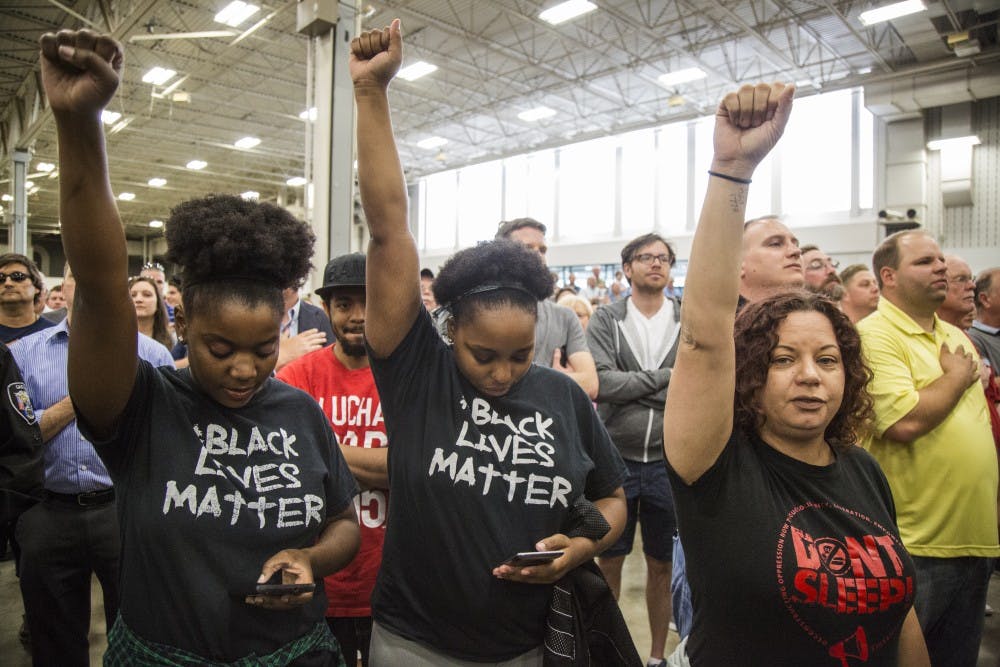 Several Black Lives Matter protestors raise fists during the Pledge of Allegiance at April 20 Trump rally at the fair grounds in Indianapolis. DN PHOTO/TRENT SCROGGINS