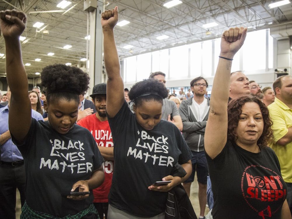 Several Black Lives Matter protestors raise fists during the Pledge of Allegiance at April 20 Trump rally at the fair grounds in Indianapolis. DN PHOTO/TRENT SCROGGINS