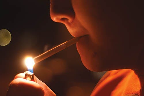 Freshman Jordan Alstoft lights a cigarette in the smoking section between LaFollette and Johnson. The Ball State Board of Trustees recently passed a measure that would ban smoking on campus.  DN FILE PHOTO BOBBY ELLIS