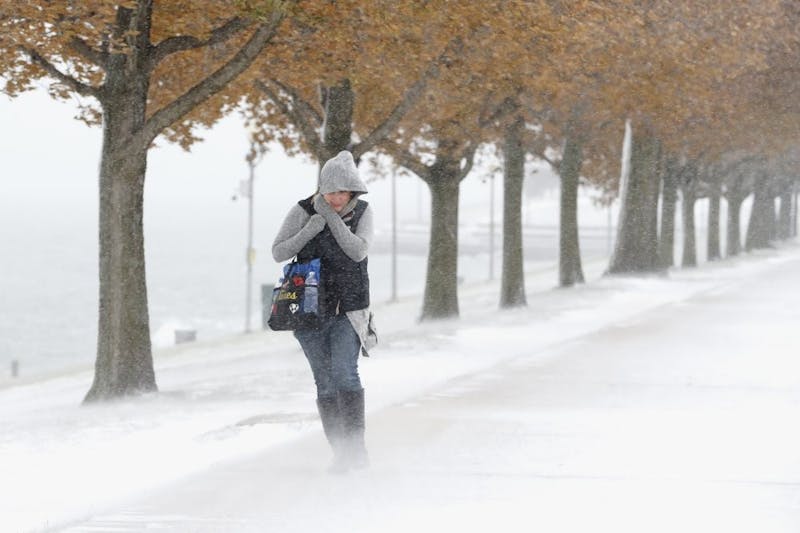A woman walking the half mile from Chicago's Adler Planetarium to the Chicago Aquarium braces herself in the stiff wind and blowing snow off Lake Michigan, Monday, Nov. 11, 2019, in Chicago. (AP Photo/Charles Rex Arbogast)