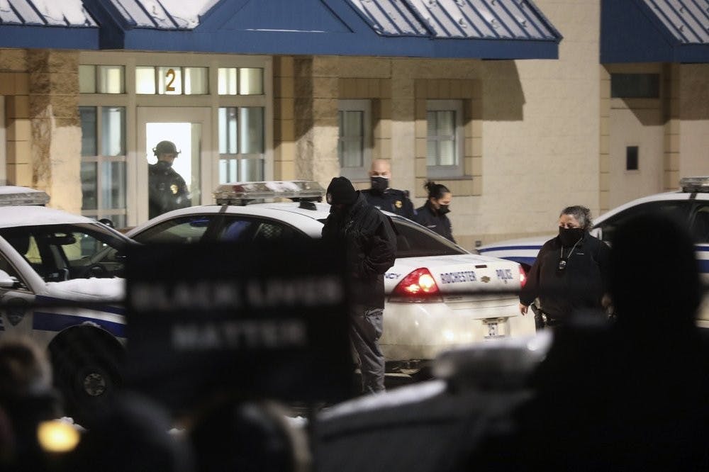 Members of Community Justice Initiative and their supporters, foreground, demonstrate, Monday, Feb. 1, 2021, in front of the Rochester Police Department's Clinton Section at N. Clinton Avenue and Upper Falls Boulevard to protest the police handcuffing and using pepper spray on a 9-year-old girl last Friday, in Rochester, N.Y. (Tina MacIntyre-Yee/Democrat & Chronicle via AP)
