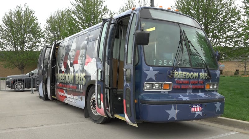 A blue bus, decorated with stars and images of historical figures, is parked with its door open.