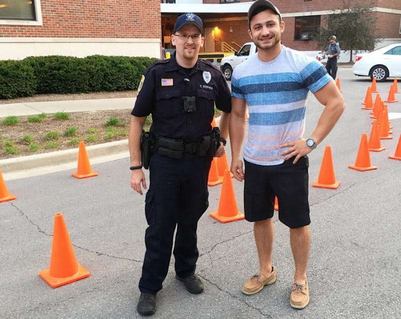 Secretary of Student Safety Drake Spangler stands with UPD at Park Hall's drunk goggle tricycle races to raise awareness of the dangers of drunk driving and safe drinking habits. Ball State SGA Instagram, Photo Courtesy