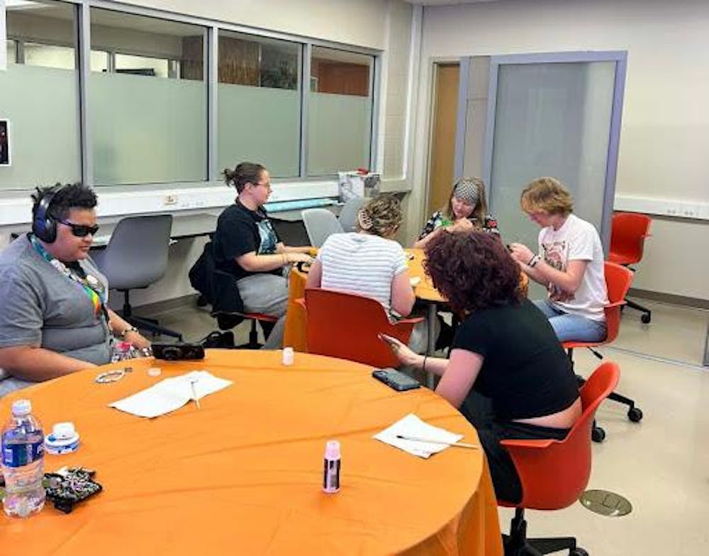 ASL club members hand-painting a symbol in American Sign Language.

