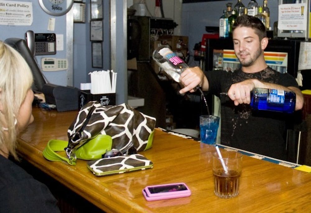 Senior theater major Adam Turkett pours a drink for a customer at the Locker Room Sunday.  Everyone will be carded to buy alcohol starting July 1.  DN PHOTO TYLER STEWART