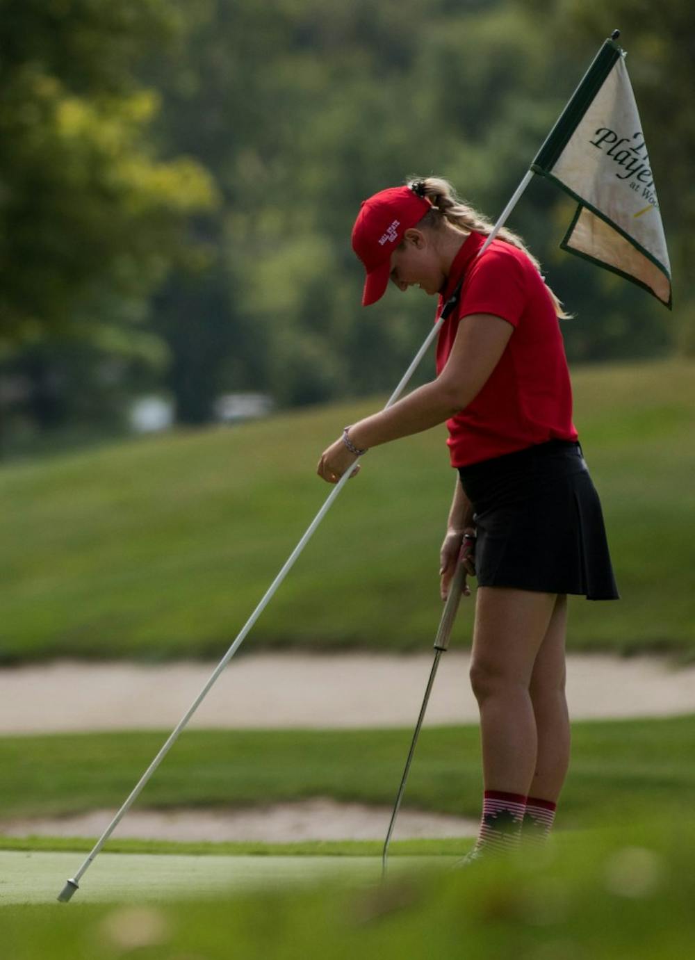 Freshman Dylann Armstrong holds the flag on the green as her opponents putt in their balls Sept. 17, 2018, at the Players Club in Yorktown, Indiana during the Cardinal Classic Golf Tournament. The Cardinals faced off against 16 other colleges in the two-day tournament. Eric Pritchett,DN