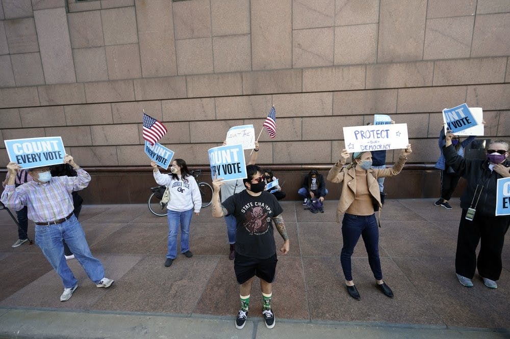 Demonstrators stand across the street from the federal courthouse in Houston, Monday, Nov. 2, 2020, before a hearing in federal court involving drive-thru ballots cast in Harris County. The lawsuit was brought by conservative Texas activists, who have railed against expanded voting access in Harris County, in an effort to invalidate nearly 127,000 votes in Houston because the ballots were cast at drive-thru polling centers established during the pandemic. (AP Photo/David J. Phillip)