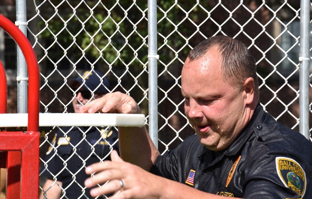 <p>Sergeant Scott Stafford climbs back up on the bench after falling into the water tank. The Dunk-a-Cop fundraiser's goal was to give back to the community and create dialogue with students. Patrick Calvert // DN</p>