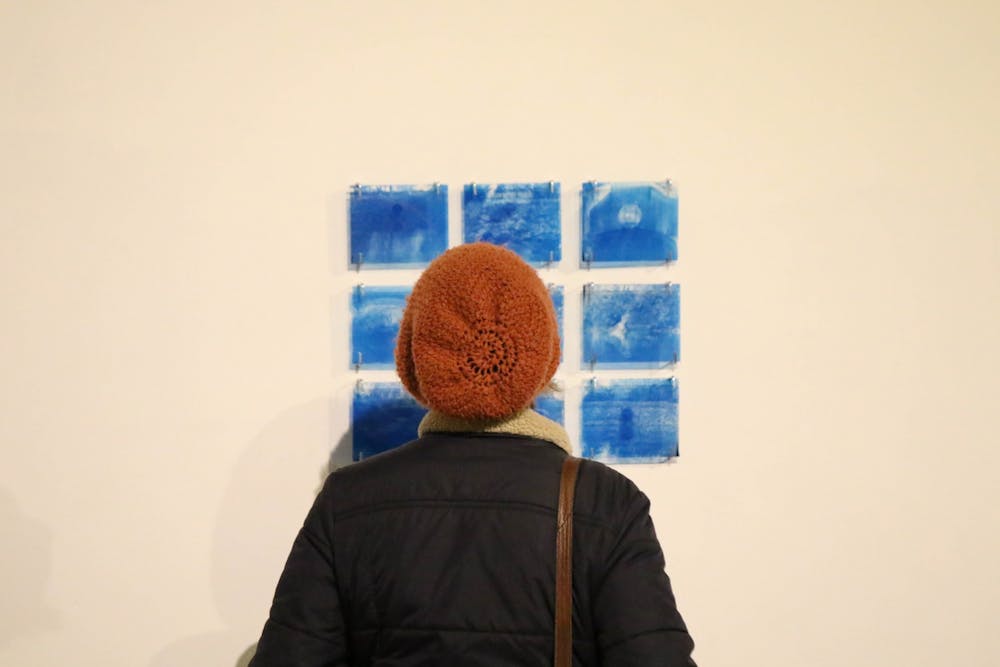 <p>A visitor looks at an art piece during "The First Guide" art gallery Nov. 18 at PlySpace in downtown Muncie. The gallery was part of a one-night-only event. <strong>Eli Houser, DN</strong></p>