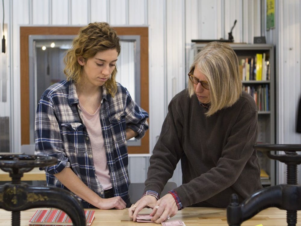 Rai Peterson shows senior actuarial science major Gipson Schabel  how to make miniature books at the Book Arts Collaborative in downtown Muncie. The makerspace also holds workshops for the community to learn about book arts skills. Emma Rogers // DN