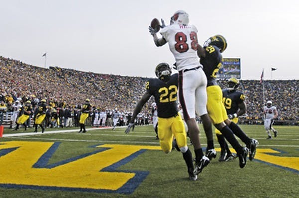 Ball State University's Darius Hill reaches above double coverage for the pass from quarterback Nate Davis during the 4th quarter of play against Michigan University at Michigan Stadium in Ann Arbor, MI. Davis' pass fell incomplete and despite driving 80 yards to the Michigan 2 yard line, the Cardinals were unable to get the ball in the endzone, which would have set them up for a 2 point conversion to tie the game. DN PHOTO/ROBERT LEISTRA