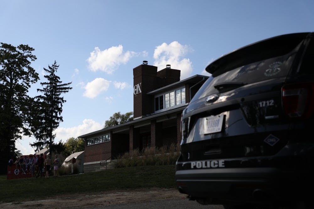 <p>Theta Chi members and friends sit outside their fraternity house Oct. 3, 2018. The Muncie Police Department sit in the driveway monitoring the house and its residents.<strong> Rebecca Slezak, DN</strong></p>
