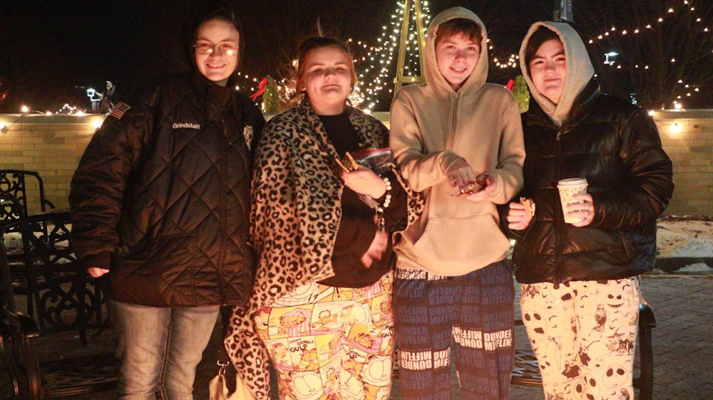 A group of friends surrounds a fire to keep warm at the Minnetrista’s Luminaria Walk 2024 Dec. 6. The group was roasting marshmallows to combat freezing temperatures. Shelby Anderson, DN