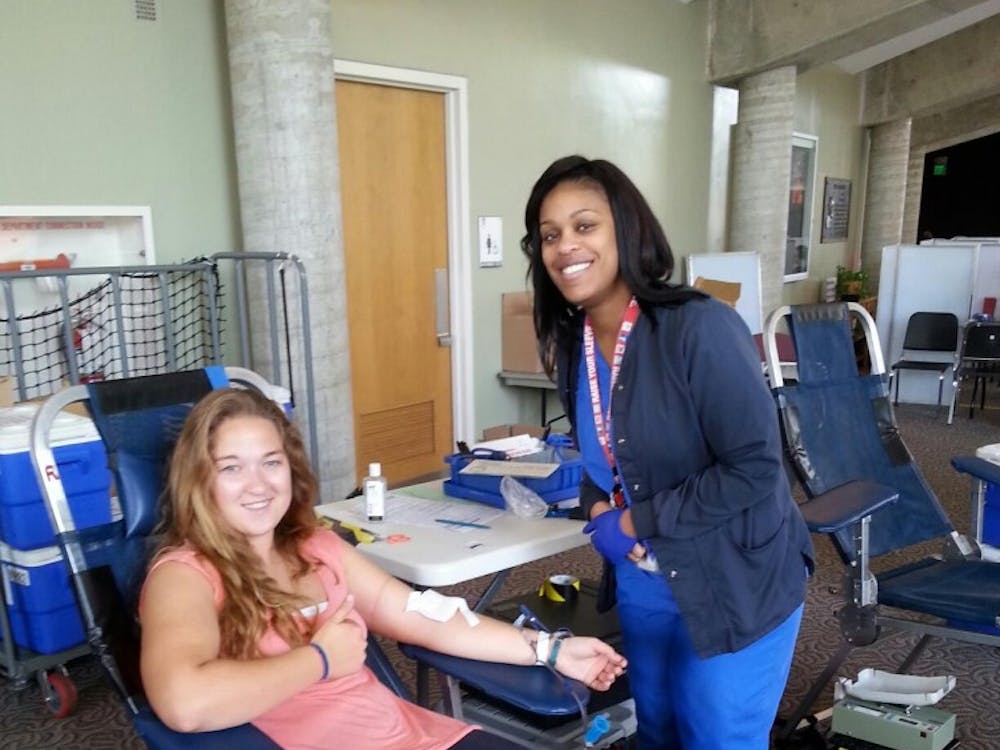 Ball State student Crystal Nichols poses for a photo while giving blood with the help of Indiana Blood Center blood technician Evadnie Turner on Sept. 9 at Pruis Hall as part of the Live to Give event. PHOTO PROVIDED BY  LUCY WEHKING