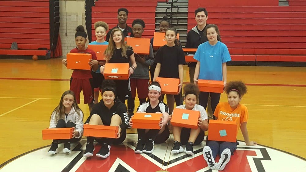 Seventh and eighth grade girls basketball teams at Southside Middle School pose with their new shows with assistant head coach Jaleel Pryuer (left) and head coach Erik Hoglund. The Interfraternity Council donated $1,500 to both programs to purchase new shoes for the season. Evan Weaver, DN