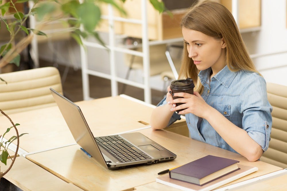 Attractive young casual businesswoman working on her laptop at the coffee shop concentrating focusing success achievement studying project startup inspiration ideas technology online internet connect