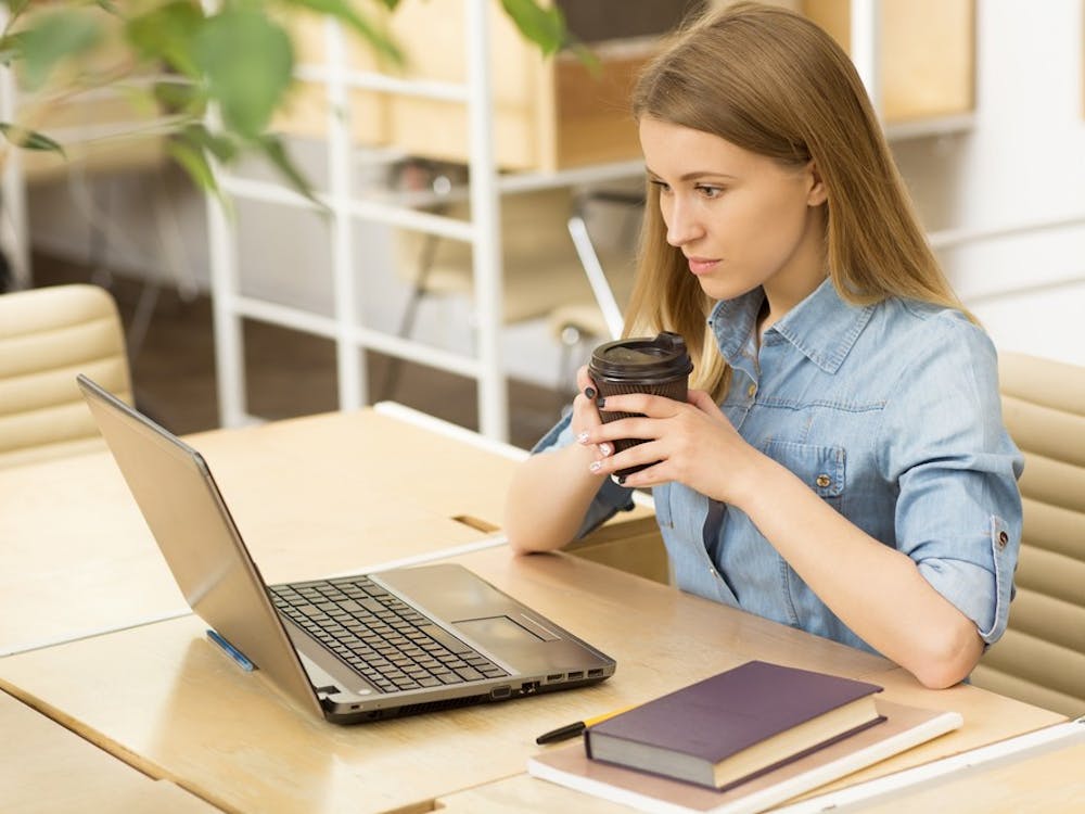 Attractive young casual businesswoman working on her laptop at the coffee shop concentrating focusing success achievement studying project startup inspiration ideas technology online internet connect