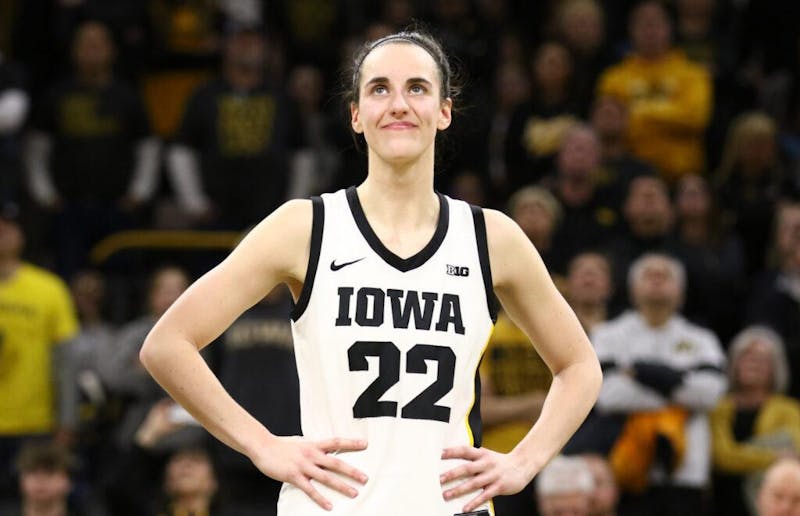 IOWA CITY, IOWA- FEBRUARY 15:  Guard Caitlin Clark #22 of the Iowa Hawkeyes listens as the crowd cheers after breaking the NCAA women's all-time scoring record during the game against the Michigan Wolverines  at Carver-Hawkeye Arena on February 15, 2024 in Iowa City, Iowa.  (Photo by Matthew Holst/Getty Images/IndianaCapitalChronicles)