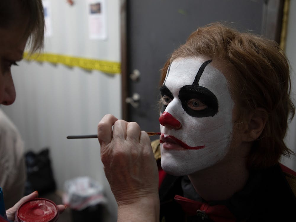 Jodie Morgan, the manager of Indy Scream Park's makeup trailer, works on painting lips onto a Midway actor's face for their costume. Indy Scream Park's makeup artists work for two hours each day before the park opens to complete the actor's full look. Jacob Musselman, DN
