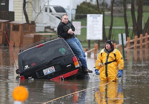 A rescue official stands with a motorist stuck in water during heavy rains and flooding in Round Lake Heights, Ill., on April 18, 2013. Forecasts from the National Weather Service have called for heavy rain tonight and Tuesday throughout much of the Midwest, adding to already flooded areas. MCT PHOTO