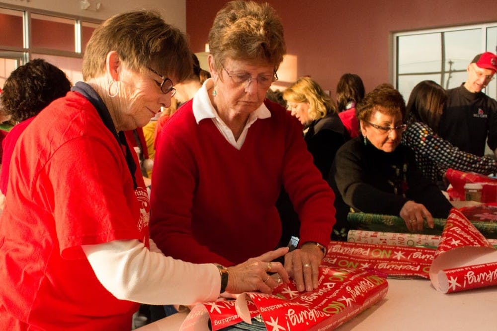 Marsha Kibby, right, and Norma Hiestand, left, wrap gifts for the Secret Families Christmas Charity on Saturday. Volunteers bought gifts at 6 a.m. at Meijer and then wrapped the gifts at Toyota of Muncie. DN PHOTO TAYLOR IRBY