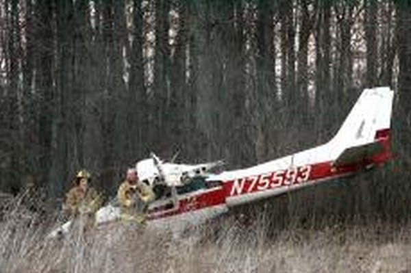 Two Hamilton Township firefighters walk past the wreckage of a single-engine Cessna airplane that made an emergency landing in a wooded area north of the Delaware County Airport on Monday evening. The pilot, Joseph Bruns of Indianpolis, suffered a separated shoulder in the crash. DN PHOTO/CHRISTOPHER WEDDLE
