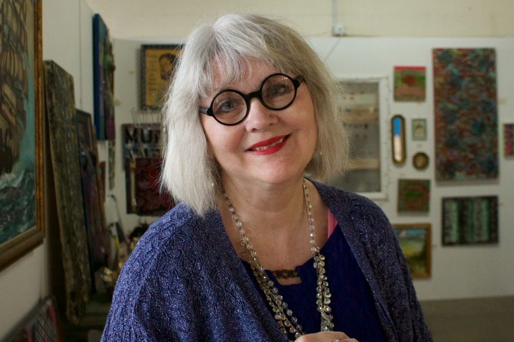 Local Muncie artist Debra Gindheart smiles in her art display, downtown at Madjax on April 23. Gindheart will be one of the six artists at the Poetry Night Salon. Rebecca Slezak, DN