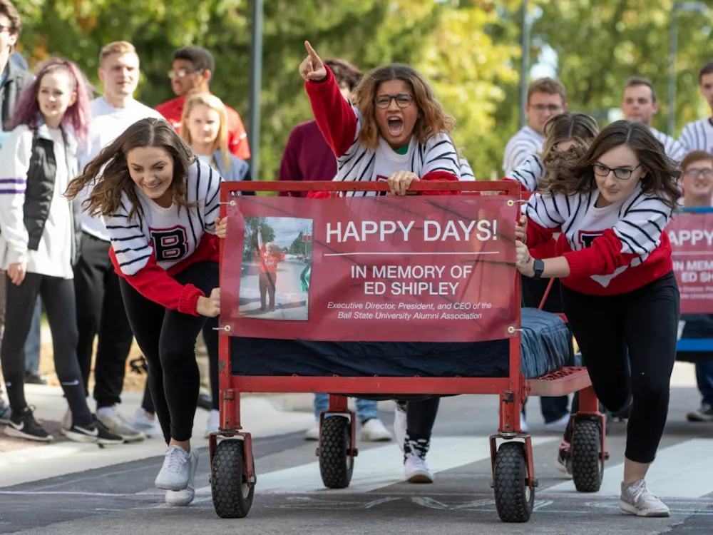 Students from the Ball State University Singers organization take off during the 2019 Ball State University Bed Race Oct. 18, on Riverside Ave. Bed races have been a Homecoming Week traditional at BSU since 1980. Kyle Crawford, Byte File