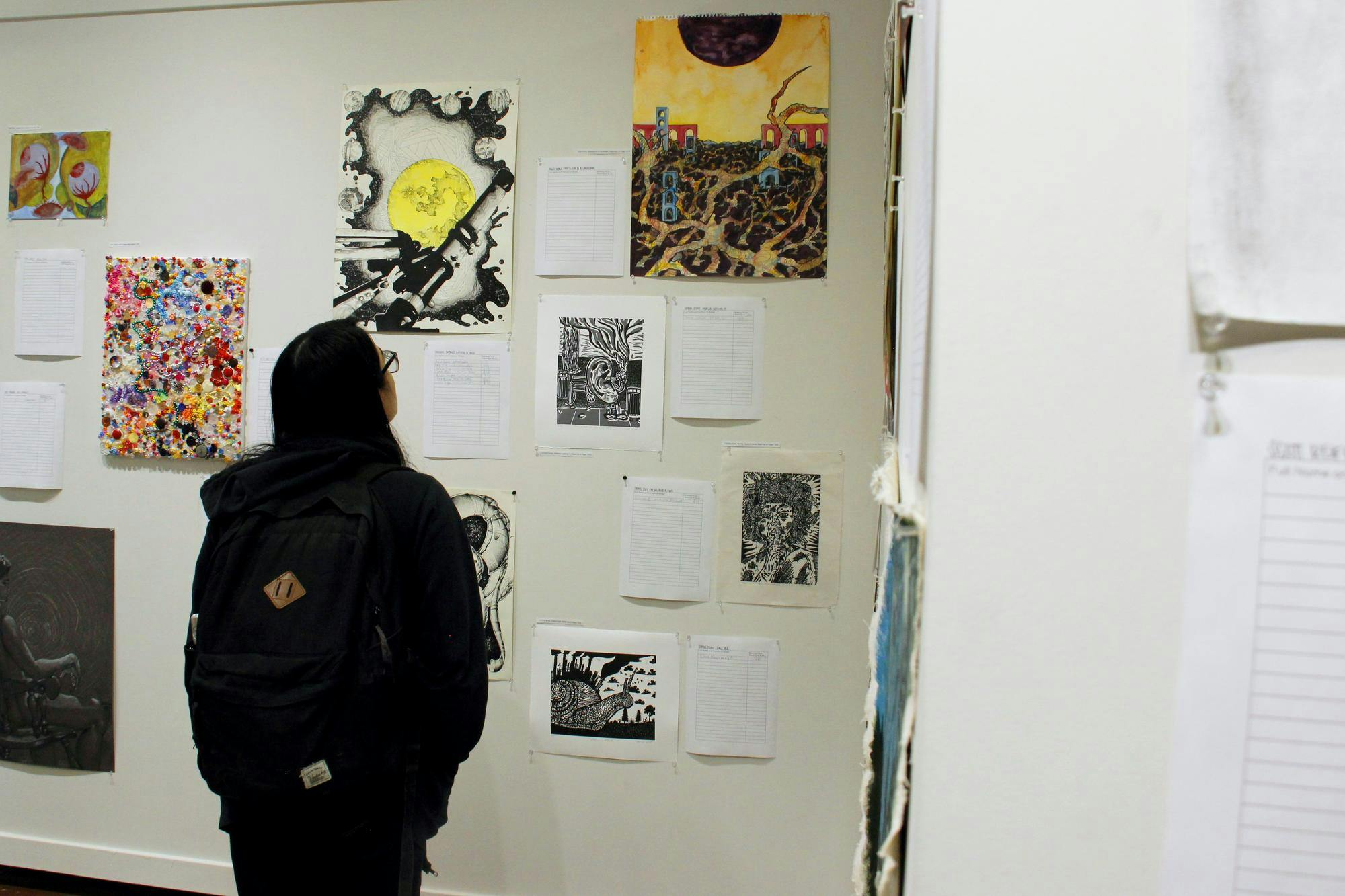 A Ball State student observes artwork on display during the "Art of Caring" show bidding April 10 in Ball State's Art and Journalism building on Ball State University's campus in Muncie, Ind. Katherine Hill, DN