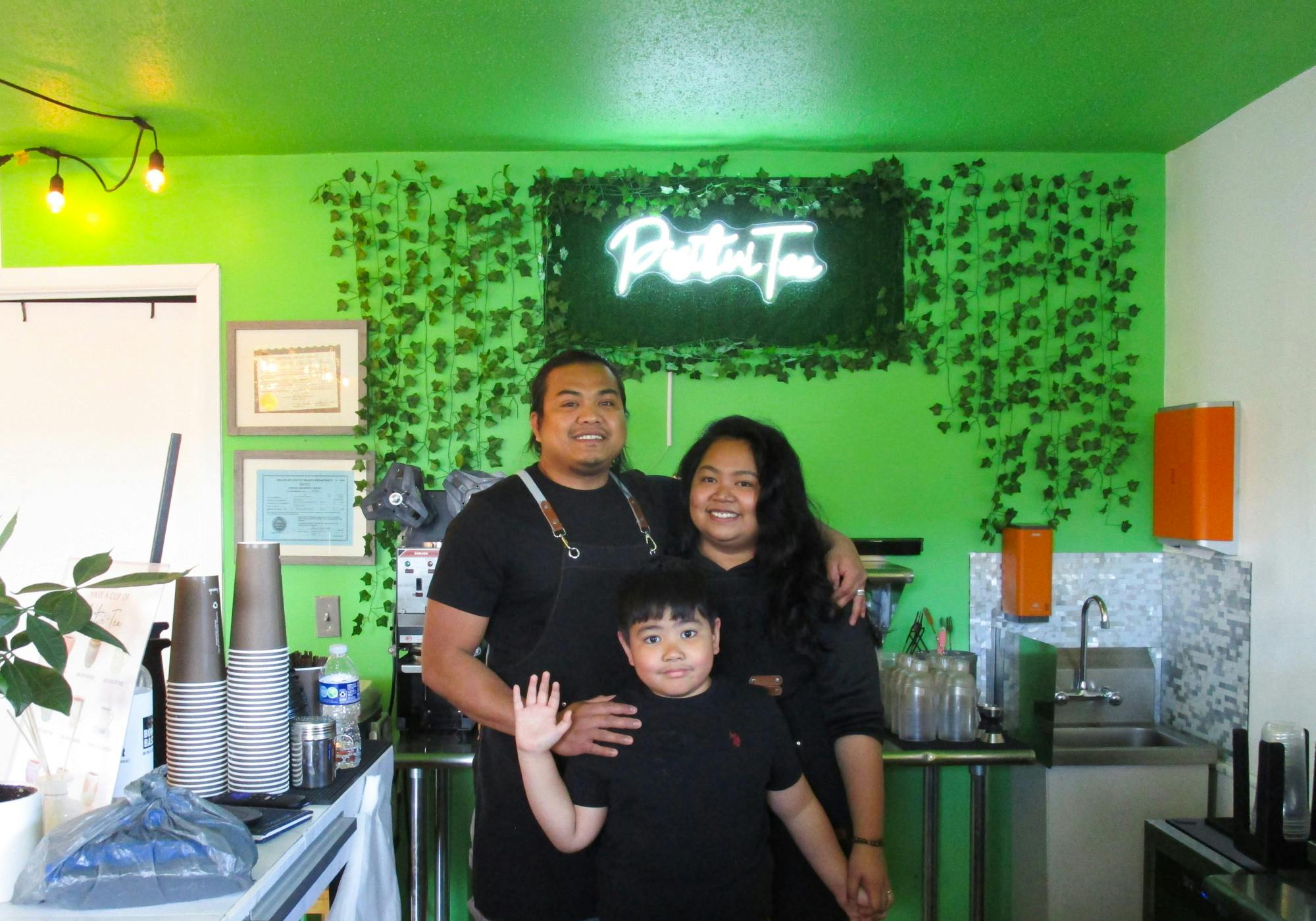 PositiviTea owners Maria and Jay R Cabasag pose with their son Ernest in front of the light up sign bearing their store&#x27;s name inside their shop Aug. 27. They set up all of the decorations for PositiviTea themselves. Scarlet Gallagher, DN