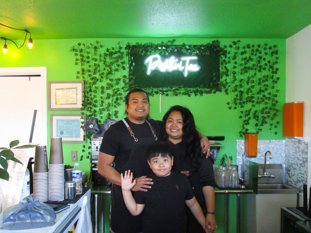 PositiviTea owners Maria and Jay R Cabasag pose with their son Ernest in front of the light up sign bearing their store&#x27;s name inside their shop Aug. 27. They set up all of the decorations for PositiviTea themselves. Scarlet Gallagher, DN