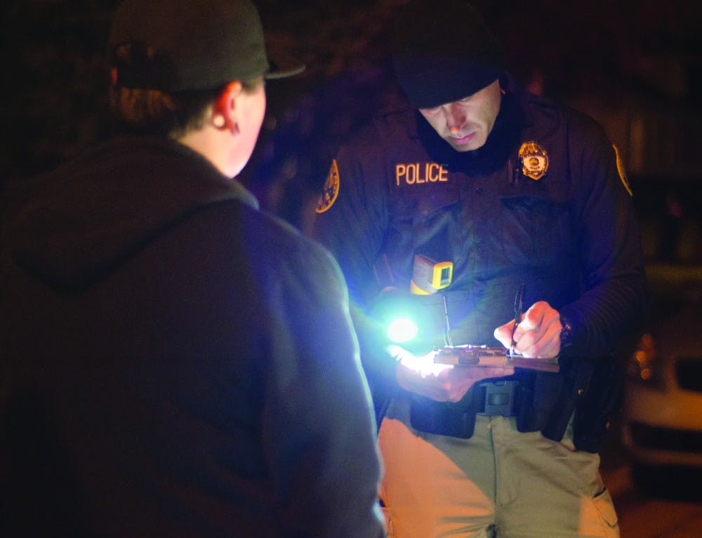Indiana State Excise officer Brandon Thomas writes a minor consumption ticket to an underage student early on Nov. 3. The student blew a .116 BAC, according to a portable Breathalyzer examination administered on scene. DN PHOTO COREY OHLENKAMP