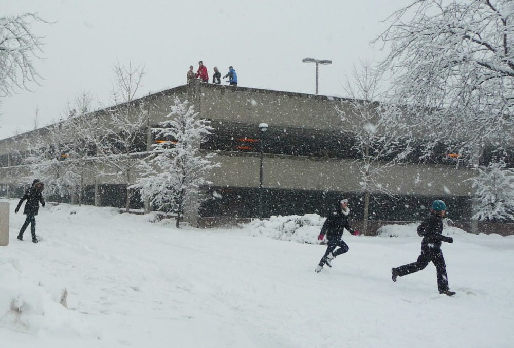 Students atop a parking garage ambush unsuspecting walkers with snowballs. The group said many of their victims played along with the prank. DN PHOTO SAM HOYT