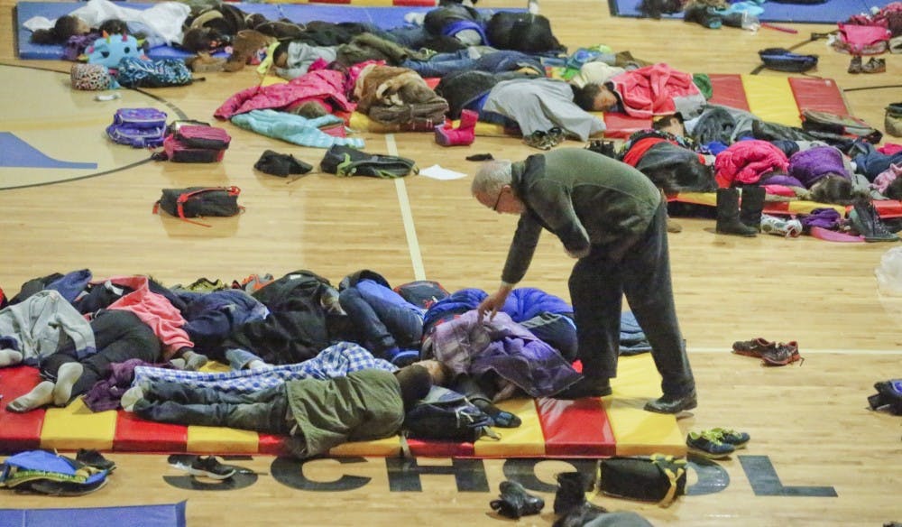 A teacher at E. Rivers Elementary School in Atlanta covers sleeping children in the gym Wednesday morning, Jan. 29, 2014, as school children were stranded overnight. (John Spink/Atlanta Journal-Constitution/MCT)