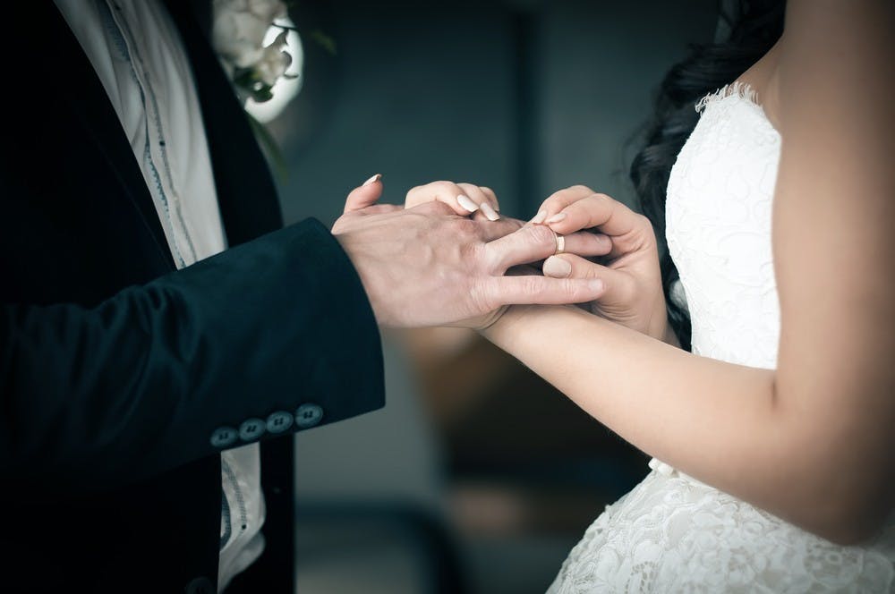 Bride puts on a wedding ring on groom's finger