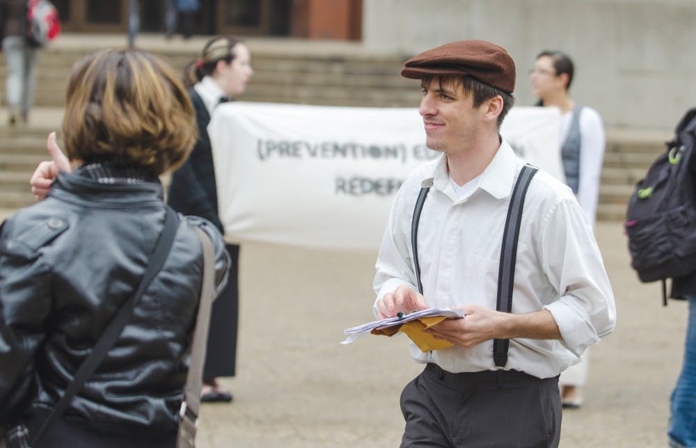 Matthew Smith, co-director of Amnesty International, hands out fliers to people encouraging them to sign a petition to advise the university to expand the sexual assault programs Dec. 4 outside of Bracken Library. Protestors adapted speeches and outfits from the 1920s to tie in the women