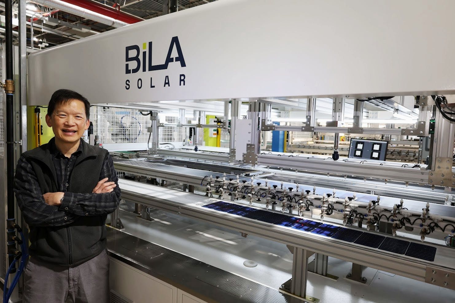 Wei-Tai Kwok, president of Bila Solar located in Indianapolis, stands inside the company’s production facility as solar panels move through an automated manufacturing line. PHOTO PROVIDED